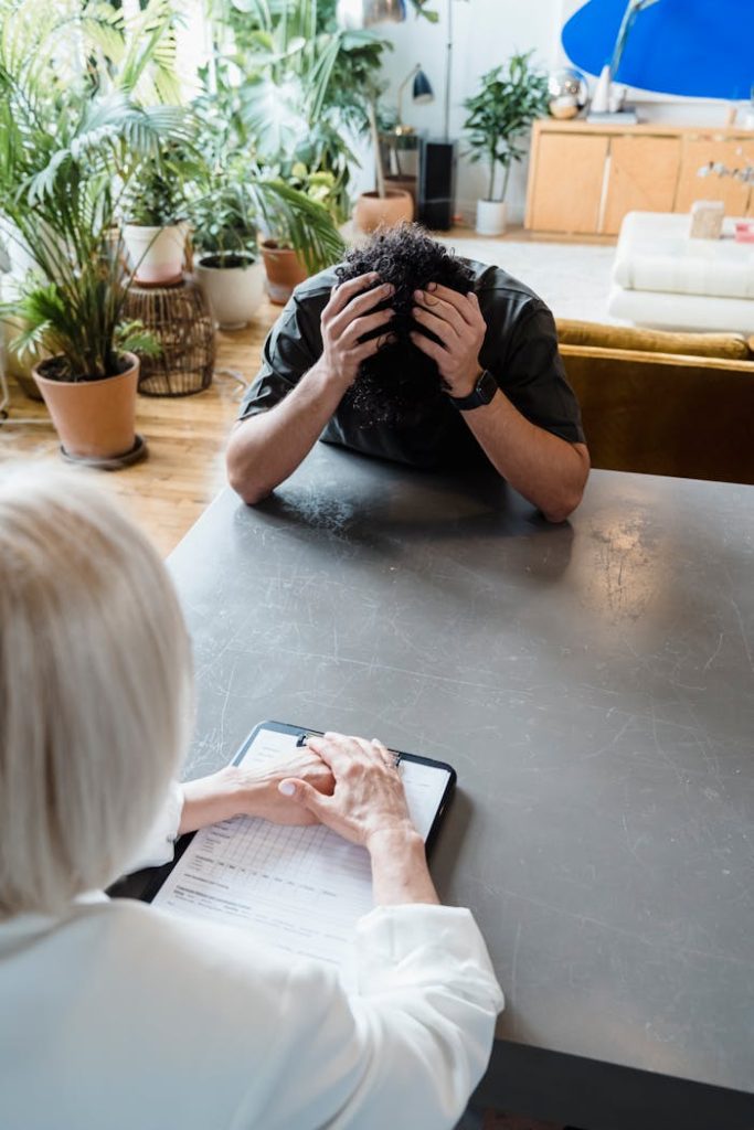 A therapist consults a distressed man in an indoor psychotherapy session.